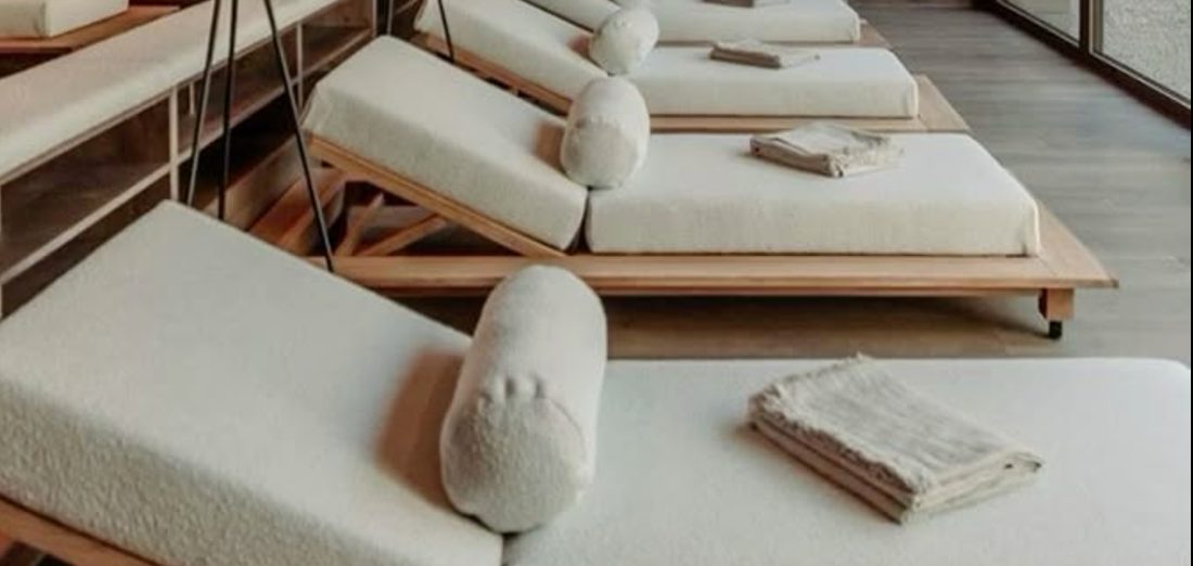 Rows of boucle-covered timber loungers with bolster cushions